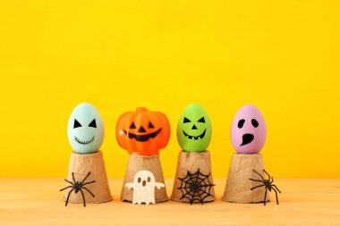 Cadılar Bayramı tatil kavramı. Komik, korkunç ve sevimli yüzü, örümcekler ahşap masa üzerinde olan renkli yumurta