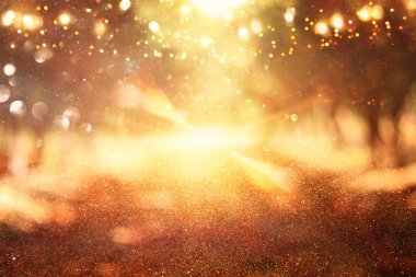 Ağaçlar arasında ışık patlaması ve parlak altın bokeh ışıklarının bulanık fotoğrafı.