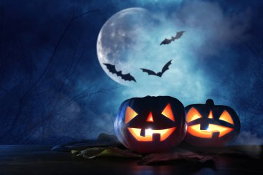 Cadılar Bayramı tatil kavramı. Gece korkunç, perili ve sisli orman, ahşap masa üzerinde kabaklar