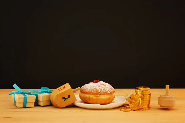 Image of jewish holiday Hanukkah with traditional doughnut and spinning top on the table