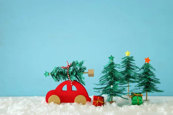 Rode Houten Auto Een Kerstboom Sneeuw Voorkant Van Blauwe Achtergrond — Stockfoto