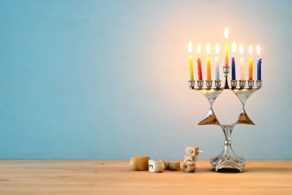 Kép a zsidó ünnep a Hanukkah háttér hagyományos spinnig felső, menóra (hagyományos kandeláberek) és égő gyertyák. — Stock Fotó