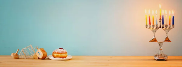 Nápis je židovský svátek Chanuka pozadí s tradičními spinnig nahoře, Menora (tradiční svícny) a hořící svíčky — Stock fotografie