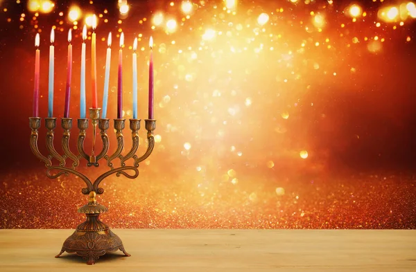 Kép a zsidó ünnep a Hanukkah háttér menorah (hagyományos kandeláberek) és gyertya, csillogó fényes háttér felett. — Stock Fotó