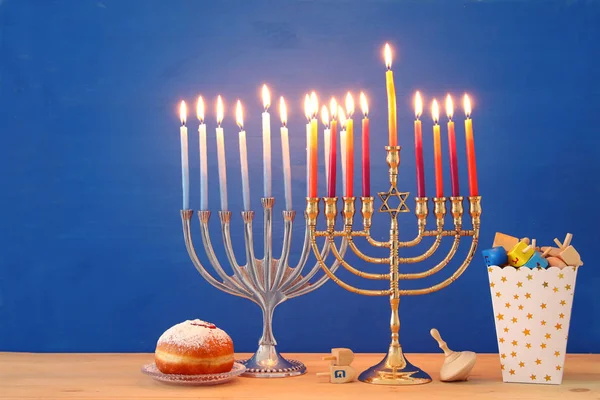 Bilden av judiska högtiden Hanukkah bakgrund med traditionella spinnig top, menorah (traditionella kandelabrar) och brinnande ljus. — Stockfoto