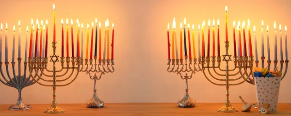 Kép a zsidó ünnep a Hanukkah háttér hagyományos spinnig felső, menóra (hagyományos kandeláberek) és égő gyertyák. — Stock Fotó