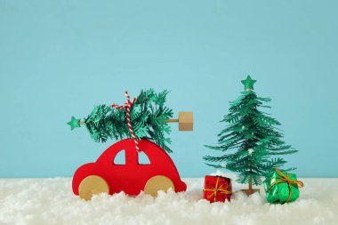 Bir Noel ağacı önünde mavi arka plan, kar üzerinde taşıyan kırmızı ahşap araba