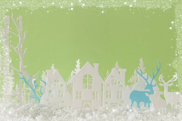 魔法のクリスマス ペーパー カット冬背景風景に、家、木、鹿とパステル グリーンの背景の前に雪. — ストック写真