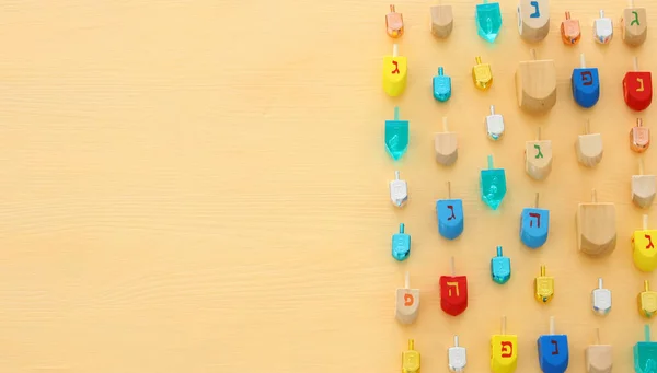 Imagem de feriado judaico Hanukkah com colecção dreidels de madeira (spinning top) sobre fundo amarelo pastel . — Fotografia de Stock