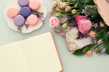 plaka macaroons ahşap masa, emprty defter ve çiçek