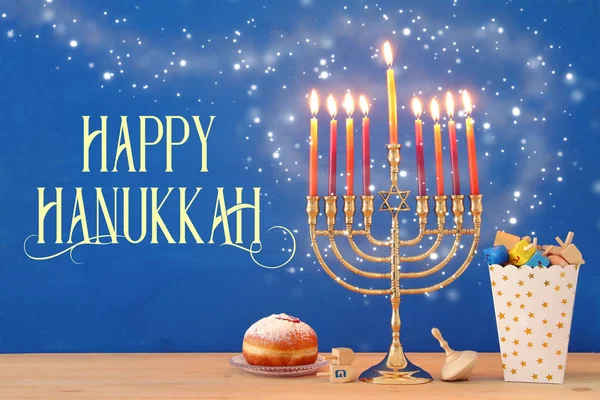 Image of jewish holiday Hanukkah background with traditional spinnig top, menorah (traditional candelabra) and burning candles