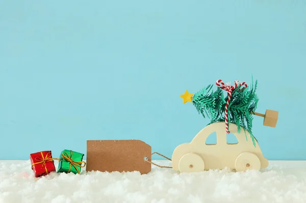 Ξύλινα Αυτοκίνητο Που Μεταφέρουν Ένα Χριστουγεννιάτικο Δέντρο Μπροστά Μπλε Φόντο — Φωτογραφία Αρχείου