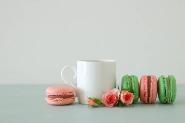 Beyaz vintage fincan kahve ve renkli macaron ya da pastel ahşap masa üzerinde acıbadem kurabiyesi