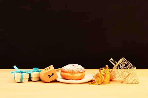 Image of jewish holiday Hanukkah with traditional doughnut and spinning top on the table