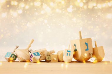 Banner of jewish holiday Hanukkah with wooden dreidels (spinning top) over glitter shiny background. clipart