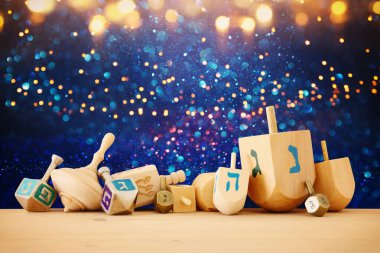 Banner of jewish holiday Hanukkah with wooden dreidels (spinning top) over glitter shiny background clipart