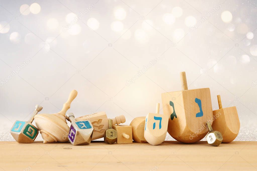 Banner of jewish holiday Hanukkah with wooden dreidels (spinning top) over glitter shiny background.