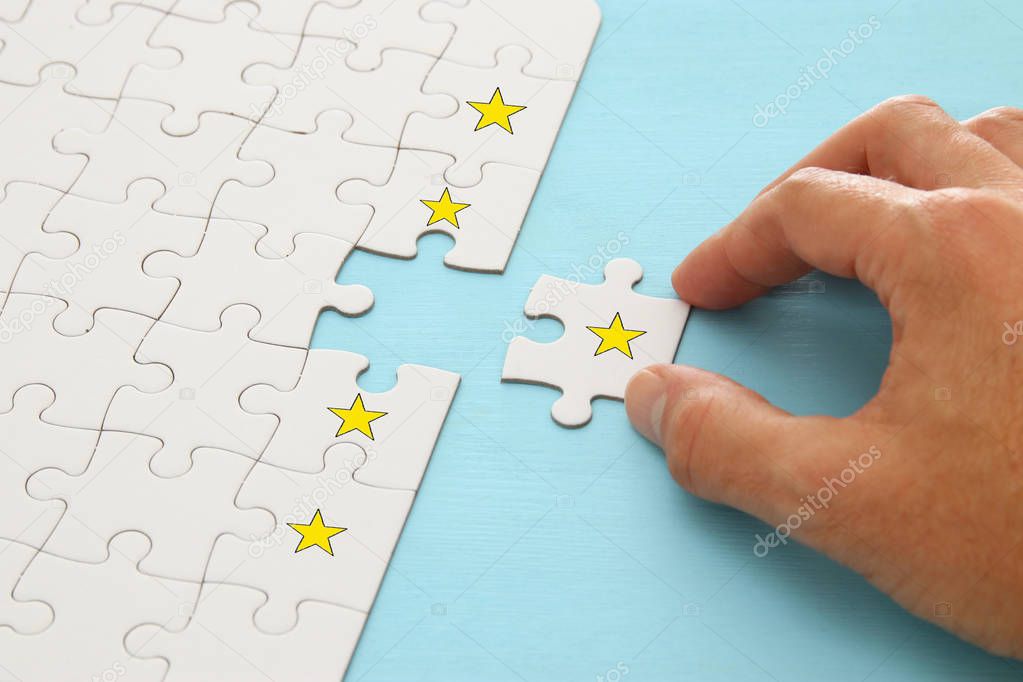 male hand putting the last piece in the puzzle. concept image of setting a five star goal. increase rating or ranking, evaluation and classification idea