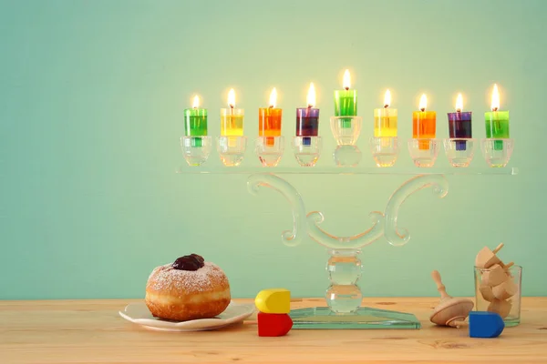 image of jewish holiday Hanukkah background with crystal menorah (traditional candelabra) and colorful oil candles