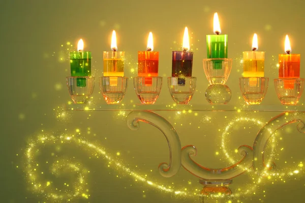 image of jewish holiday Hanukkah background with crystal menorah (traditional candelabra) and colorful oil candles