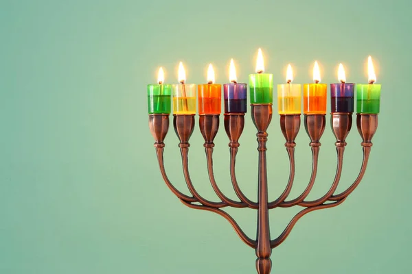 image of jewish holiday Hanukkah background with menorah (traditional candelabra) and colorful oil candles