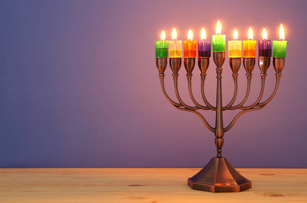 image of jewish holiday Hanukkah background with menorah (traditional candelabra) and colorful oil candles