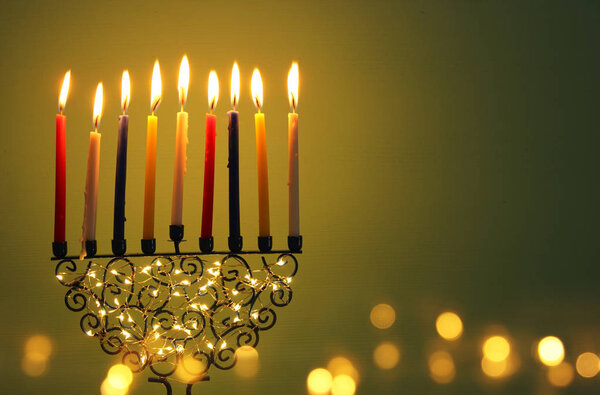 image of jewish holiday Hanukkah background with menorah (traditional candelabra) and colorful oil candles