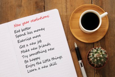 Defter, ahşap Resepsiyon üzerinde kahve ile yeni yıl kararları listesinin üstten görünüm