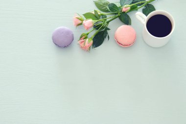 Üstten görünüm görüntüsünü beyaz fincan kahve ve renkli macaron ya da pastel ahşap arka plan üzerinde acıbadem kurabiyesi