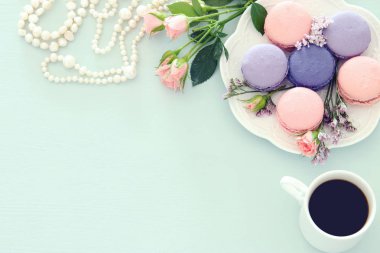 Üstten görünüm görüntüsünü beyaz fincan kahve ve renkli macaron ya da pastel ahşap arka plan üzerinde acıbadem kurabiyesi