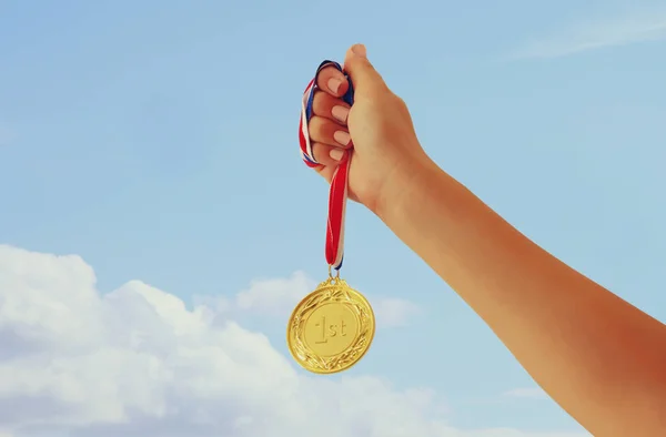 Mano Mujer Levantada Sosteniendo Medalla Oro Contra Cielo Premio Concepto — Foto de Stock