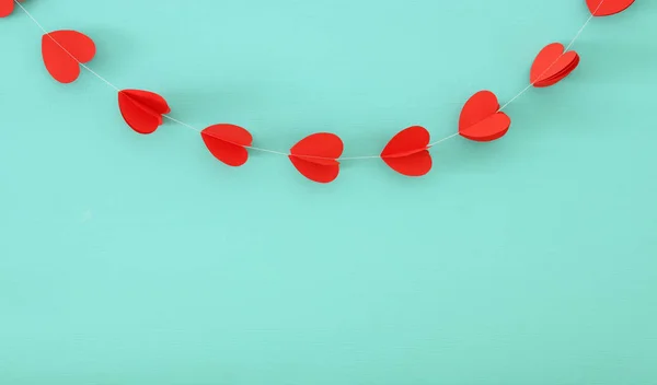 Aftelkalender voor Valentijnsdag achtergrond. harten garland ophanging aan de voorzijde van de blauwe houten achtergrond. — Stockfoto