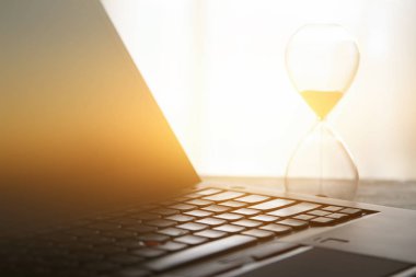 Laptop üzerinde ahşap masa başında ofis, işyeri veya ev ve kum saati görüntüsü. Filtre vintage