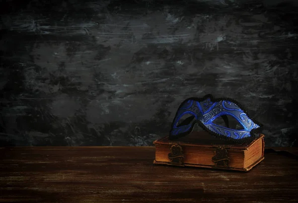 暗い背景の木フロントにヴィンテージの古い本でエレガントなロイヤル ブルーのベネチアン マスクのイメージ — ストック写真