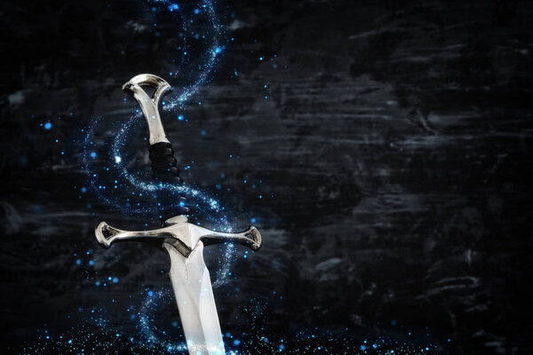 low key image of silver sword with magical lights. fantasy medieval period