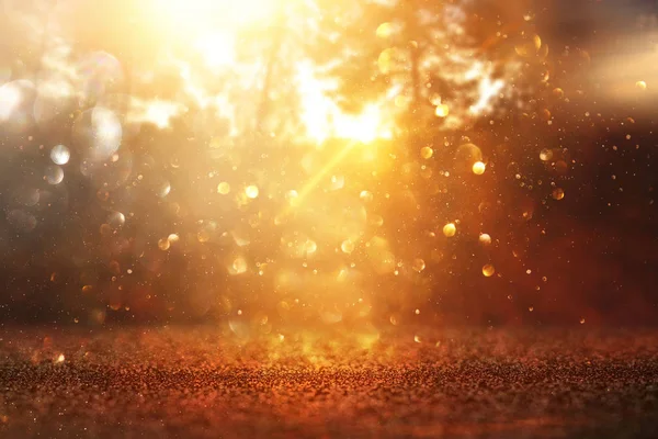 blurred abstract photo of light burst among trees and glitter golden bokeh lights