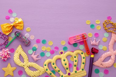 Purim kutlama kavram (Yahudi karnaval tatil) mor, pembe ahşap arka plan üzerinde. Üstten görünüm