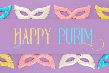 Purim kutlama kavram (Yahudi karnaval tatil) mor, pembe ahşap arka plan üzerinde. Üstten görünüm