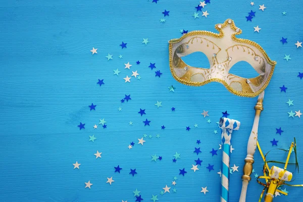 狂欢节派对庆祝概念与优雅的黄金面具上的坚持在蓝色木制背景和星星 顶视图 — 图库照片