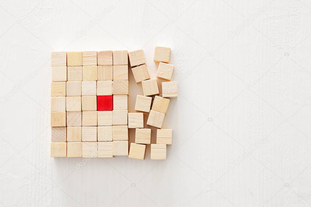 One different red cube block among wooden blocks. Individuality, leadership and uniqueness concept