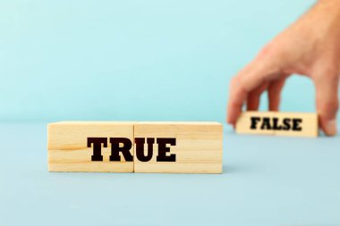 bir adam doğru veya yanlış kavramı el malzeme çekme ahşap küpleri metin ile ahşap mavi arka plan üzerinde