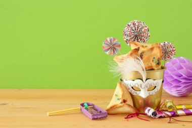 Purim kutlama kavram (Yahudi karnaval tatil) ahşap masa ve yeşil arka plan üzerinde.