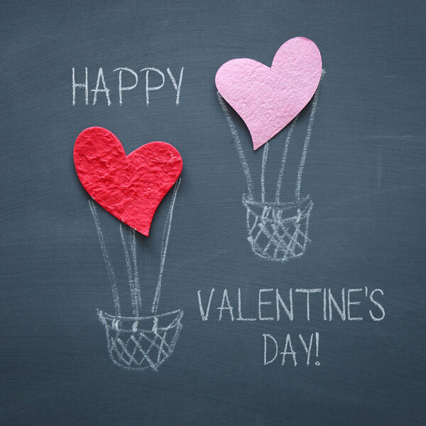Valentine's day concept. pink and red paper hearts as air balloon over blackboard