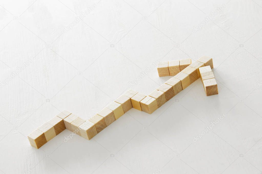 wooden cubes shaped like growing graph, over white textured background