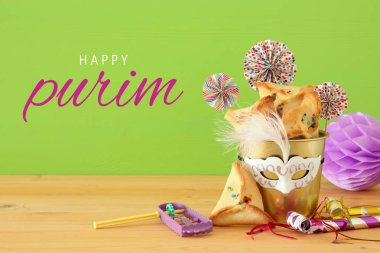 Purim kutlama kavram (Yahudi karnaval tatil) ahşap masa ve yeşil arka plan üzerinde.