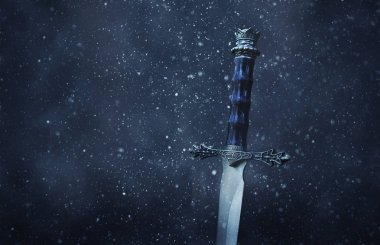 gizemli ve büyülü Gotik karlı siyah arka plan üzerinde gümüş kılıç fotoğrafı. Ortaçağ Dönemi kavramı