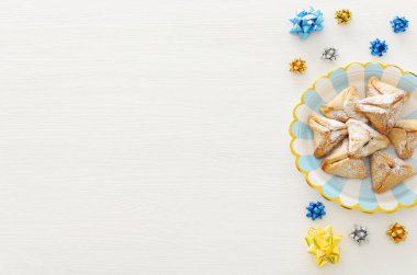 Purim kutlama kavramı (Yahudi karnaval tatil). Geleneksel hamantaschen çerez levha ve beyaz ahşap masa üzerinde