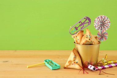 Purim kutlama kavram (Yahudi karnaval tatil) ahşap masa ve yeşil arka plan üzerinde.