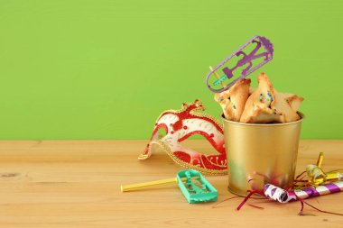 Purim kutlama kavram (Yahudi karnaval tatil) ahşap masa ve yeşil arka plan üzerinde.