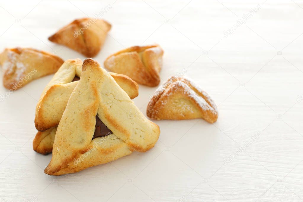 Purim celebration concept (jewish carnival holiday). Traditional hamantaschen cookies over white wooden table